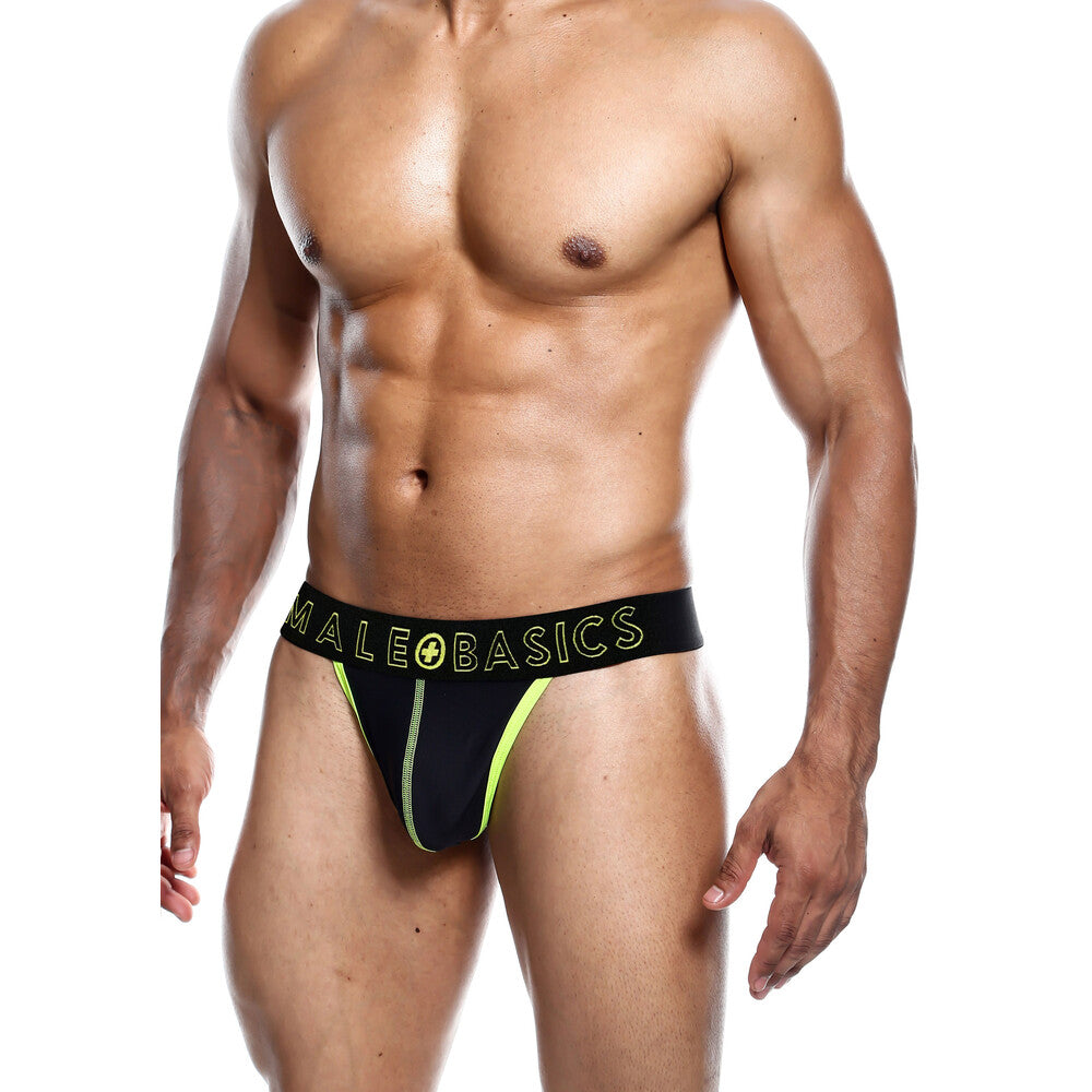 Muscular male model wearing black and neon yellow thong underwear with MaleBasics branding, representing men’s lingerie and intimate apparel